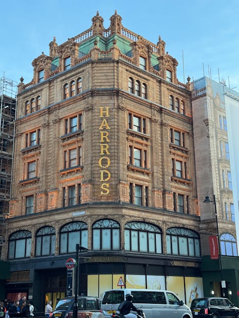 The image shows a corner of a historic, three-story building with a pale cream-colored façade and tall sash windows with white frames and decorative molding. The ground level features a dark green shopfront with large glass windows and a door, with a sign above reading 'HAN COLLECTION.' A small black square sign attached to the building displays the name 'HAN COLLECTION,' and a security camera is mounted above the storefront. A narrow street sign indicates the location as 'Galen Place,' positioned on the building’s corner. The environment appears urban, with the building situated on a quiet street. The overall scene is lit by natural daylight, with mild shadows indicating a partly cloudy sky. The style and setting suggest an area where independent retail or service businesses operate, often requiring occasional rubbish removal or private waste handling, which can be managed by services like Rubbish Removal Knightsbridge, supporting cleaner and more efficient waste disposal consistent with local regulatory standards.
